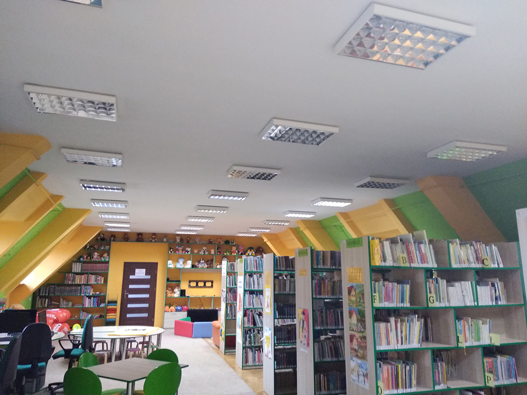  Wnętrze Oddziału dla Dzieci - kolorowe regały z książkami, na pierwszym planie u dołu kolorowy dywan 